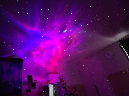 Customer photo: the projector casting a purple nebula and green stars on a bedroom ceiling