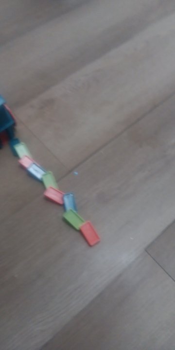 Customer photo: a trail of colorful dominoes laid out by the train on a wood floor