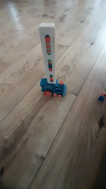 Customer photo: the blue domino train with its cartridge of dominoes on the floor