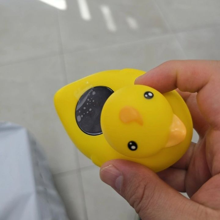 Customer photo: the duck bath thermometer with its temperature display lit, held in a hand
