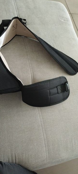 Customer photo: the black belt of the hip seat carrier resting on a sofa