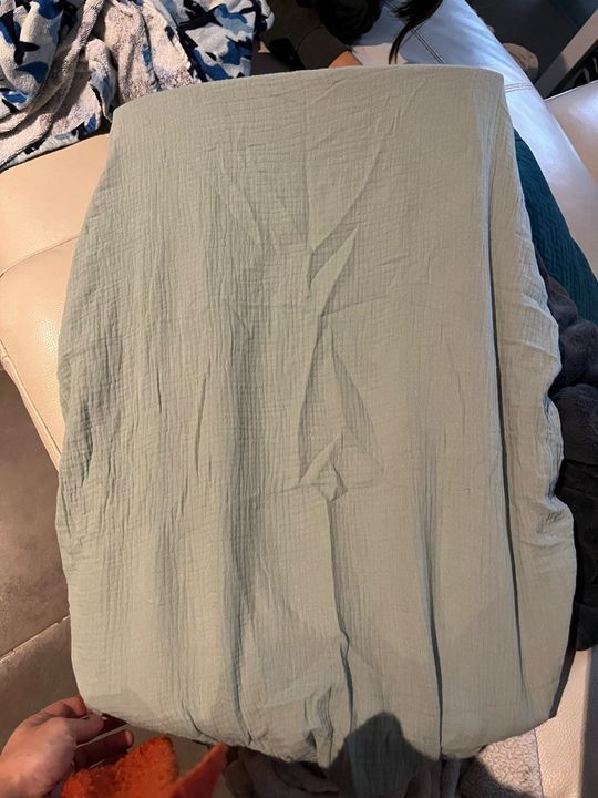 Customer photo: a sage green muslin cover held up to show the crinkled texture