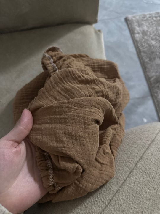 Customer photo: the tan muslin cover held in a hand