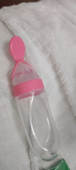 Customer photo: the pink feeder resting on a white fluffy rug