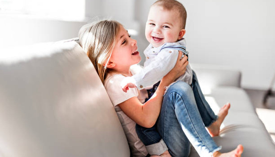 Sibling holding laughing baby