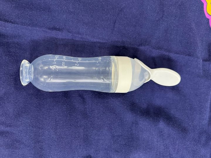 Customer photo: the feeder with a white spoon tip on dark blue fabric