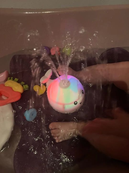 Customer photo: the whale sprinkler toy glowing and spraying water in a bath with a child