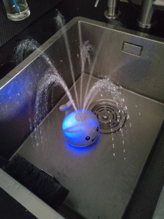 Customer photo: the whale sprinkler toy lit up and spraying water in a kitchen sink