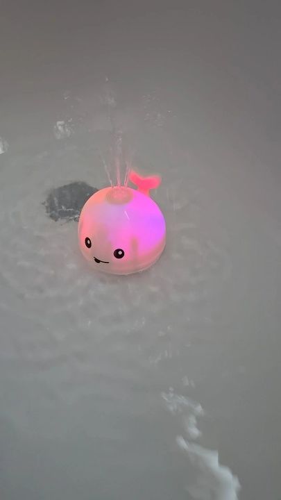 Customer photo: the whale sprinkler toy glowing and spraying water in a bathtub