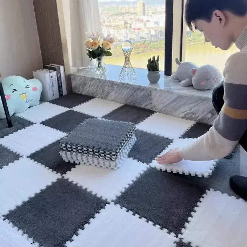 Plush Baby Floor Mat tiles in dark grey and white being assembled, with a stack of extra tiles
